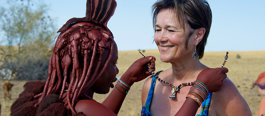 Tourist receives a beautiful beaded necklace from a Himba woman in Namibia