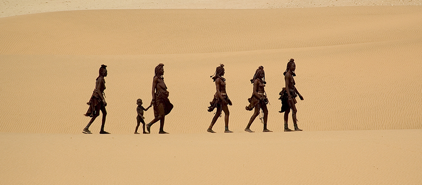 Semi-nomadic Himba people walking through the desert at Serra Cafema