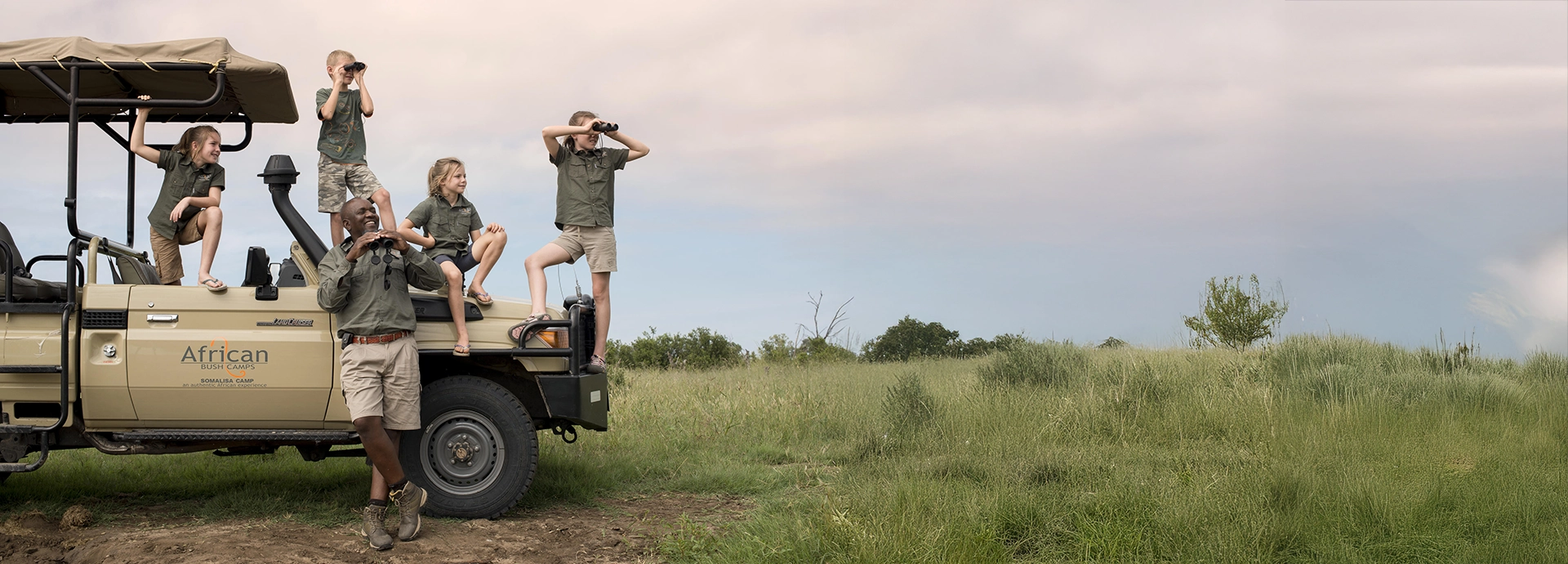 Young boy sits poolside watching a wild elephant stroll past the deck at Croc’s Nest, South Luangwa.