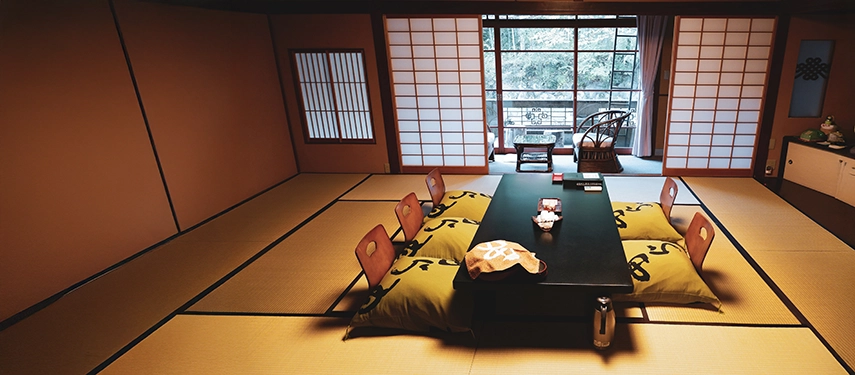A traditional tatami-mat dining room with low seating and shoji screens, reflecting the calm elegance of a classic Japanese ryokan interior.