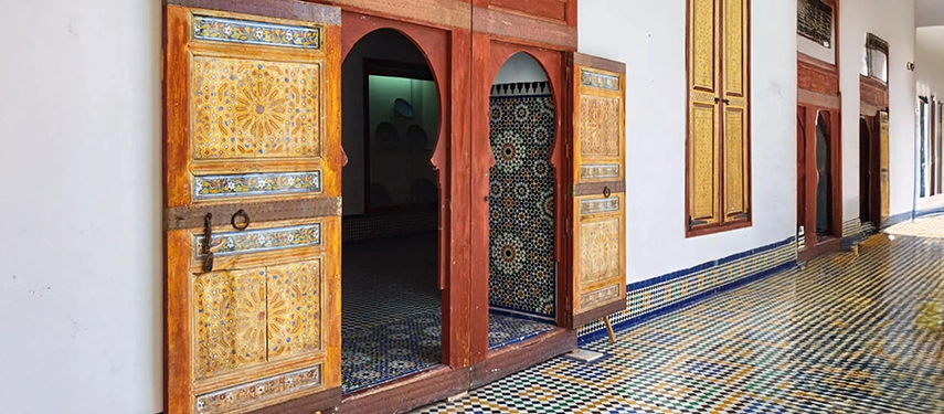Traditional Moroccan doors with intricate geometric patterns and colourful tiled flooring at Dar Batha in Fès.