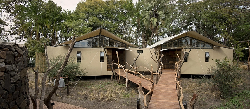 Twin canvas and timber family suites at Thorntree River Lodge connected by a wooden walkway in a riverside setting.