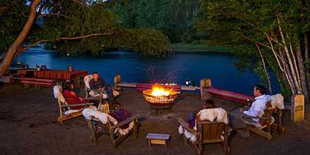 Guests gathered around an outdoor fire on the banks of Liucura River in Chile's Lake District