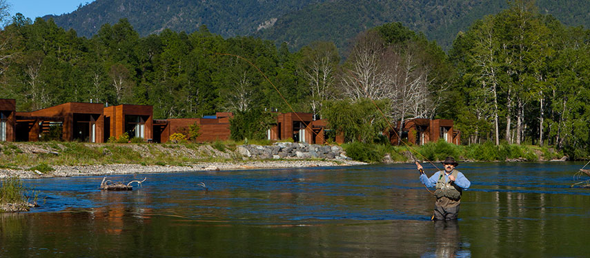Tourist fly fishing on Liucura River in Chile's Lake District with snowcapped mountains in the background